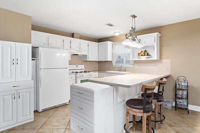 kitchen featuring a breakfast bar area, a peninsula, white appliances, a sink, and white cabinetry