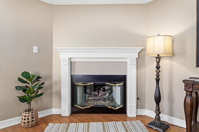 details with crown molding, baseboards, wood finished floors, and a glass covered fireplace