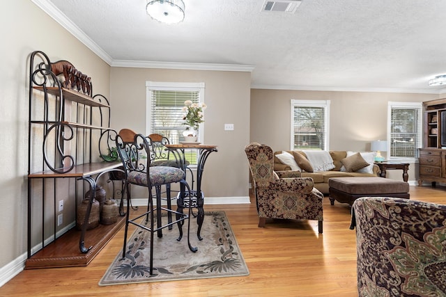 dining room with a textured ceiling, ornamental molding, wood finished floors, and baseboards