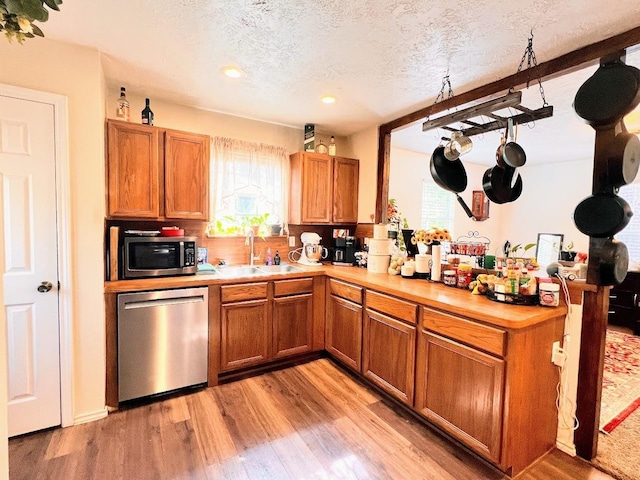 kitchen with sink, a textured ceiling, appliances with stainless steel finishes, and light hardwood / wood-style flooring