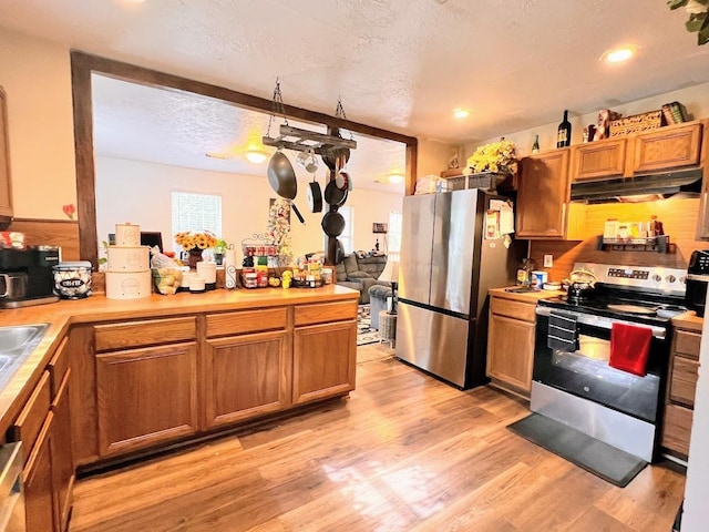 kitchen with light hardwood / wood-style flooring, a textured ceiling, and appliances with stainless steel finishes