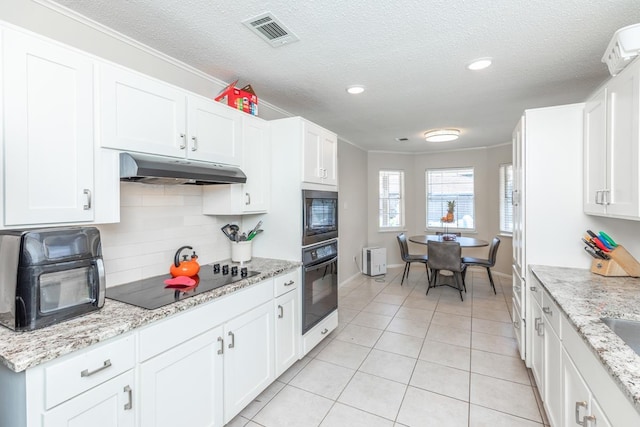 kitchen with white cabinets, light stone countertops, ornamental molding, and black appliances