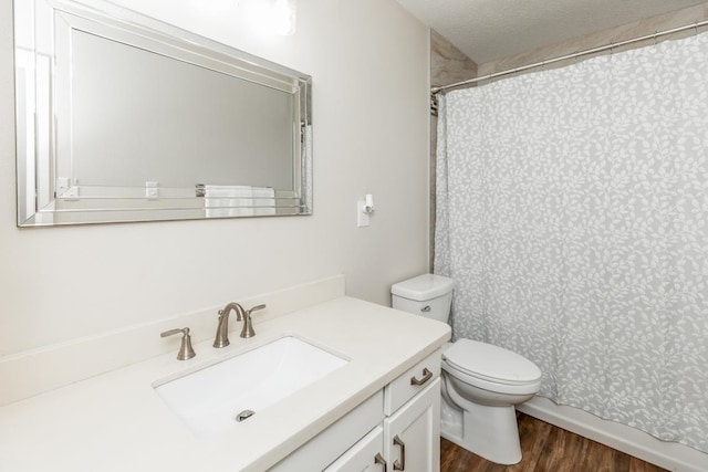 bathroom with hardwood / wood-style floors, vanity, a textured ceiling, and toilet