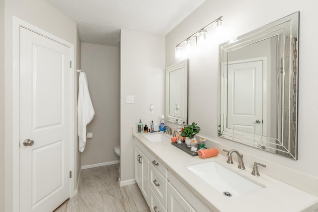 bathroom with vanity, toilet, and a textured ceiling