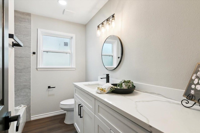 bathroom with toilet, baseboards, wood finished floors, and vanity