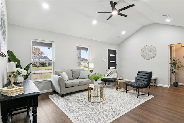 living room featuring a wealth of natural light, vaulted ceiling, baseboards, and wood finished floors