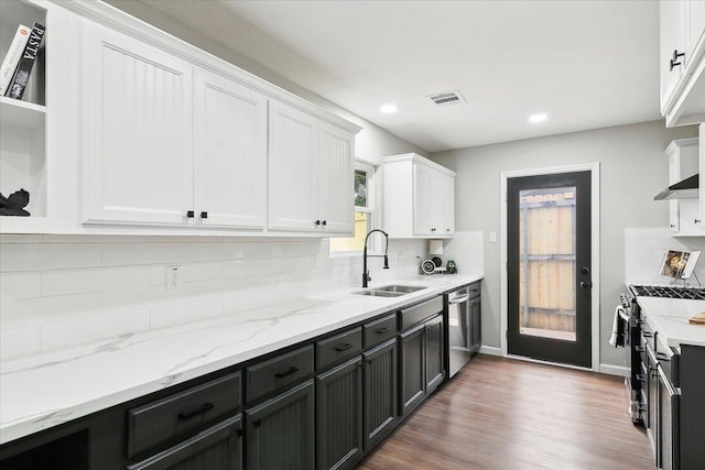 kitchen with appliances with stainless steel finishes, white cabinetry, backsplash, and a sink