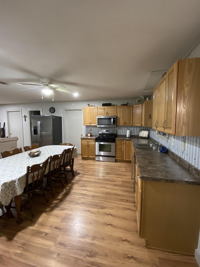 kitchen with ceiling fan, sink, stainless steel appliances, light hardwood / wood-style flooring, and backsplash