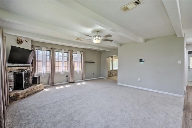 unfurnished living room with visible vents, beam ceiling, arched walkways, ceiling fan, and a brick fireplace