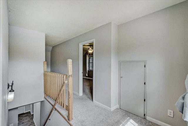 corridor featuring carpet flooring, an upstairs landing, and baseboards