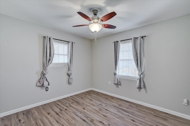 empty room featuring wood finished floors, baseboards, and ceiling fan