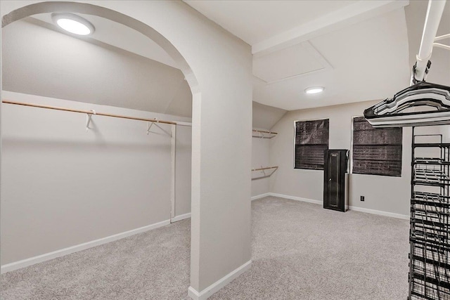 spacious closet featuring arched walkways, lofted ceiling, and carpet floors