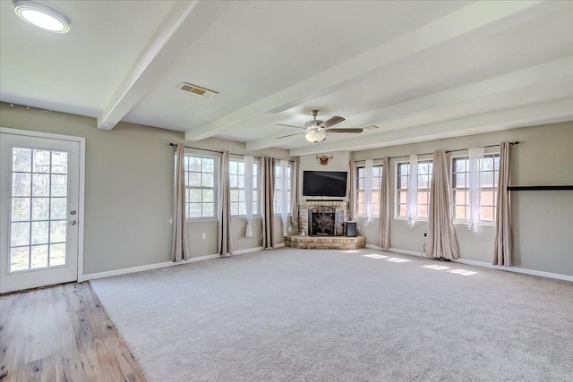 unfurnished living room featuring a wealth of natural light, baseboards, beam ceiling, and a fireplace