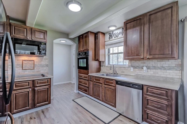 kitchen with baseboards, light countertops, light wood-style floors, black appliances, and a sink