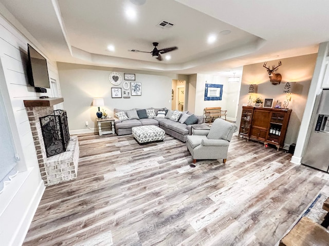 4885 Silver Leaf Dr, Orange, TX 77630 - living room featuring a tray ceiling, light wood-type flooring, a ceiling fan, a brick fireplace, and recessed lighting