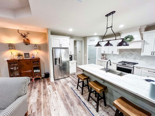 4885 Silver Leaf Dr, Orange, TX 77630 - kitchen with appliances with stainless steel finishes, white cabinetry, light wood-style flooring, backsplash, and a kitchen breakfast bar