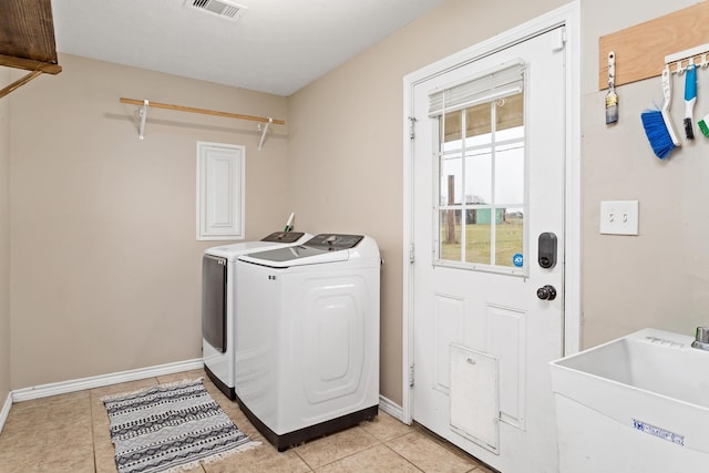 washroom with visible vents, a sink, washer and dryer, light tile patterned floors, and laundry area