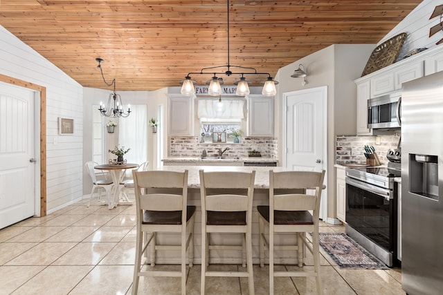 kitchen with backsplash, appliances with stainless steel finishes, light tile patterned floors, wood ceiling, and vaulted ceiling