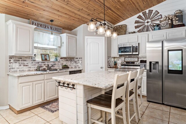 kitchen with wood ceiling, light tile patterned floors, appliances with stainless steel finishes, white cabinets, and a sink