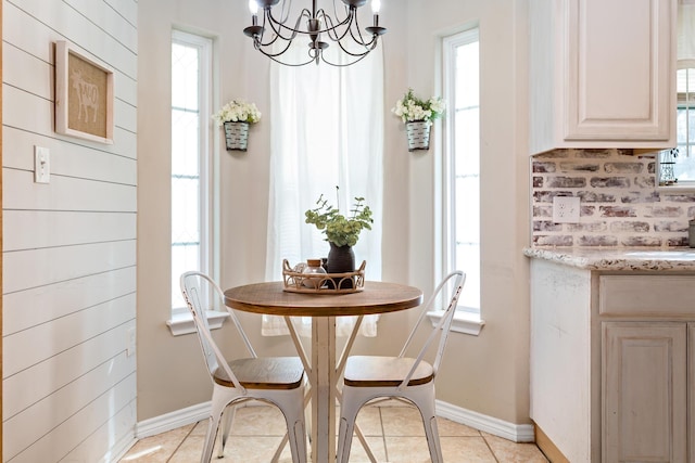 dining space featuring an inviting chandelier, light tile patterned floors, baseboards, and plenty of natural light