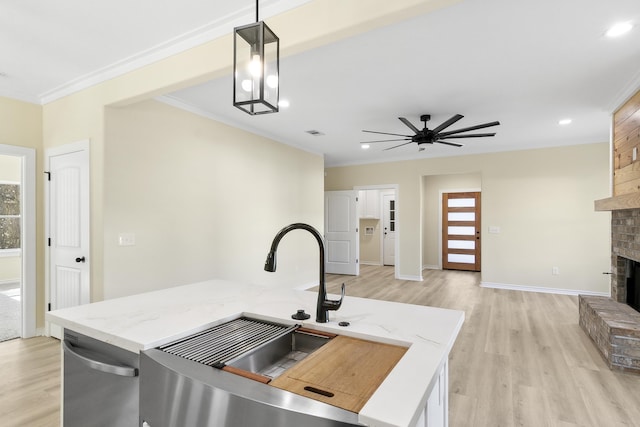 103 Ned, Lumberton, TX 77657 - kitchen featuring ornamental molding, light wood-style floors, a fireplace, stainless steel dishwasher, and pendant lighting