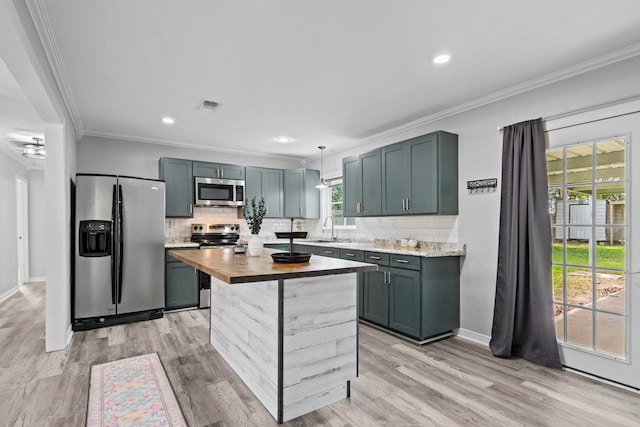 kitchen with appliances with stainless steel finishes, a sink, decorative backsplash, light wood-type flooring, and ornamental molding