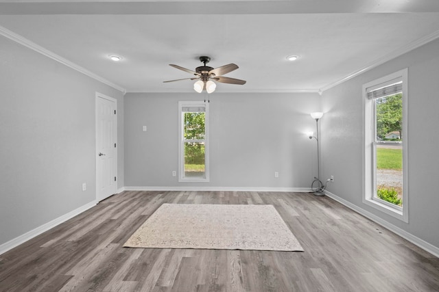 unfurnished living room with ornamental molding, plenty of natural light, wood finished floors, baseboards, and a ceiling fan