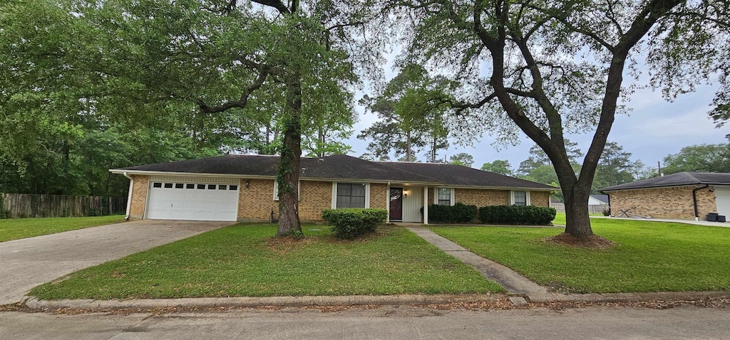single story home featuring concrete driveway, an attached garage, fence, brick siding, and a front lawn