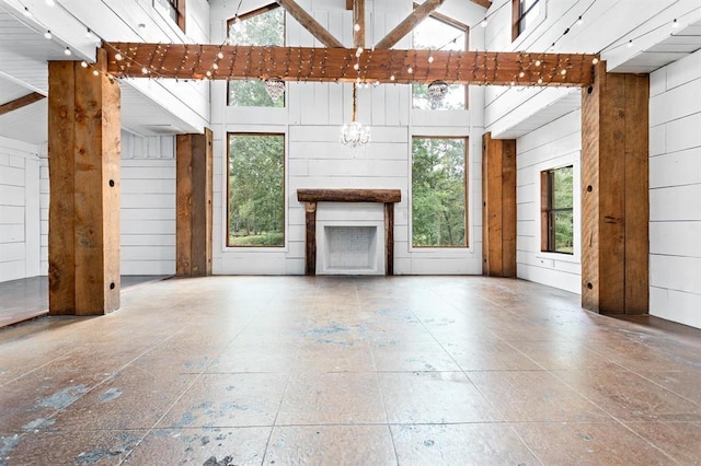 unfurnished living room with wood walls and high vaulted ceiling