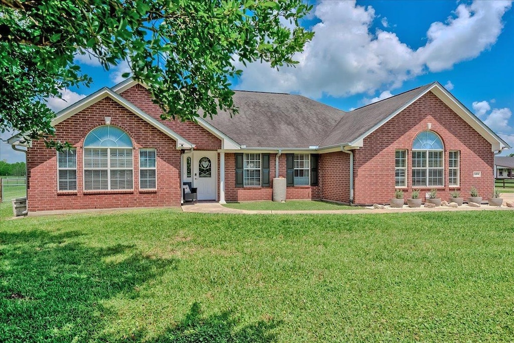 ranch-style house featuring a front yard, a shingled roof, and brick siding