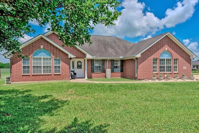 ranch-style house featuring a front yard, a shingled roof, and brick siding