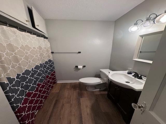 bathroom featuring vanity, a textured ceiling, hardwood / wood-style flooring, and toilet