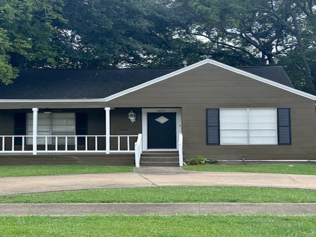 ranch-style home featuring covered porch and a front lawn