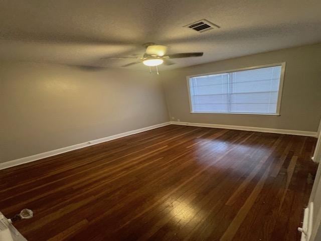 empty room with ceiling fan, dark hardwood / wood-style flooring, and a textured ceiling