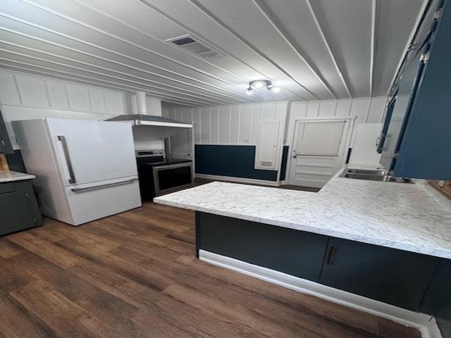 kitchen featuring sink, dark hardwood / wood-style floors, white fridge, extractor fan, and range