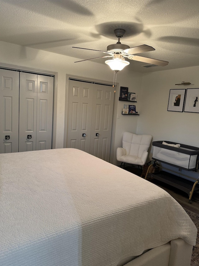 bedroom with ceiling fan, a textured ceiling, and multiple closets