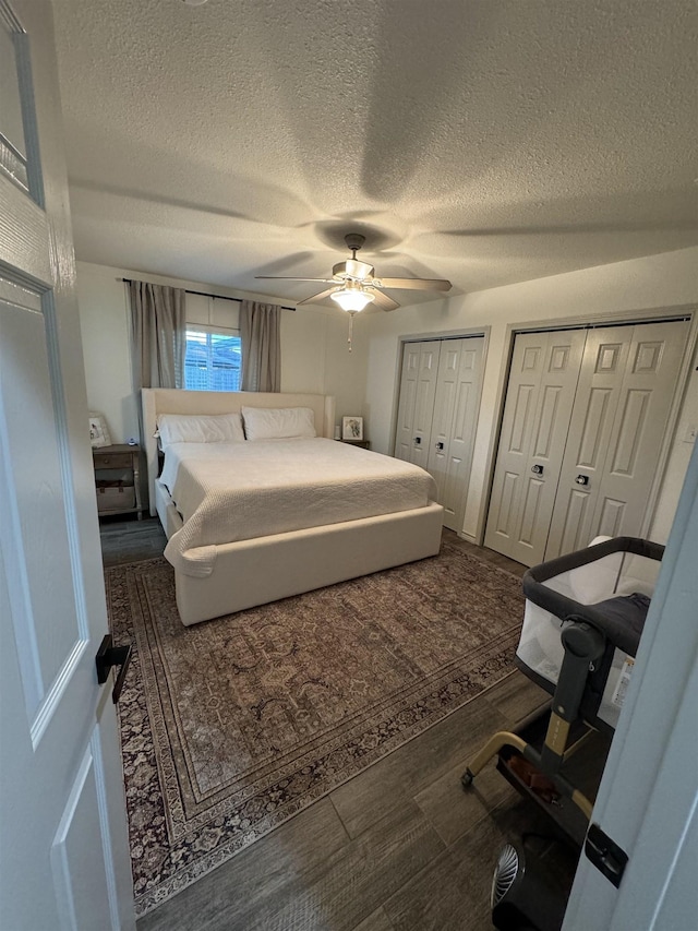 bedroom with a textured ceiling, ceiling fan, and multiple closets