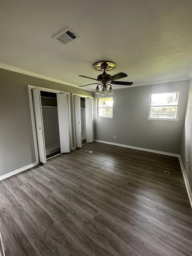 unfurnished bedroom featuring dark wood-type flooring, ceiling fan, and multiple windows