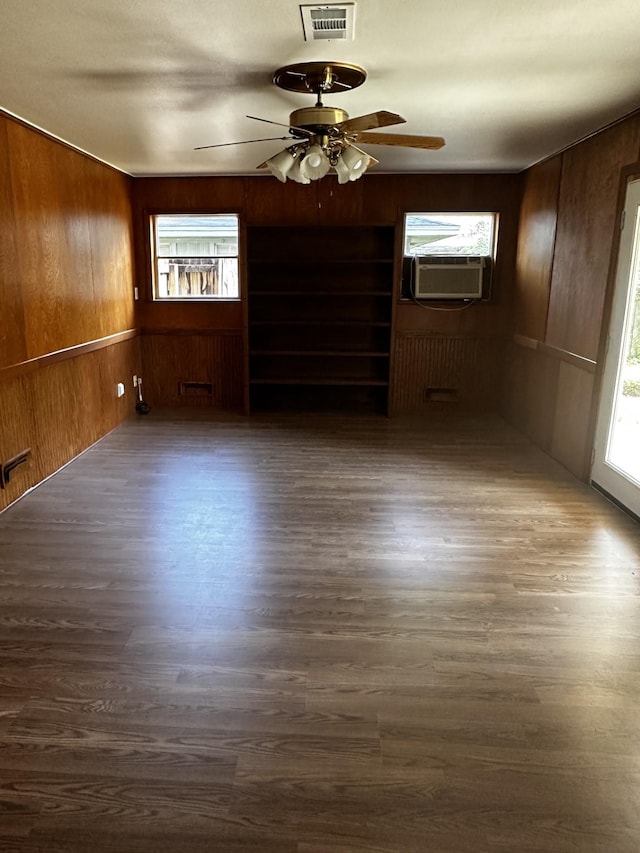 spare room with dark hardwood / wood-style flooring, wooden walls, ceiling fan, and cooling unit