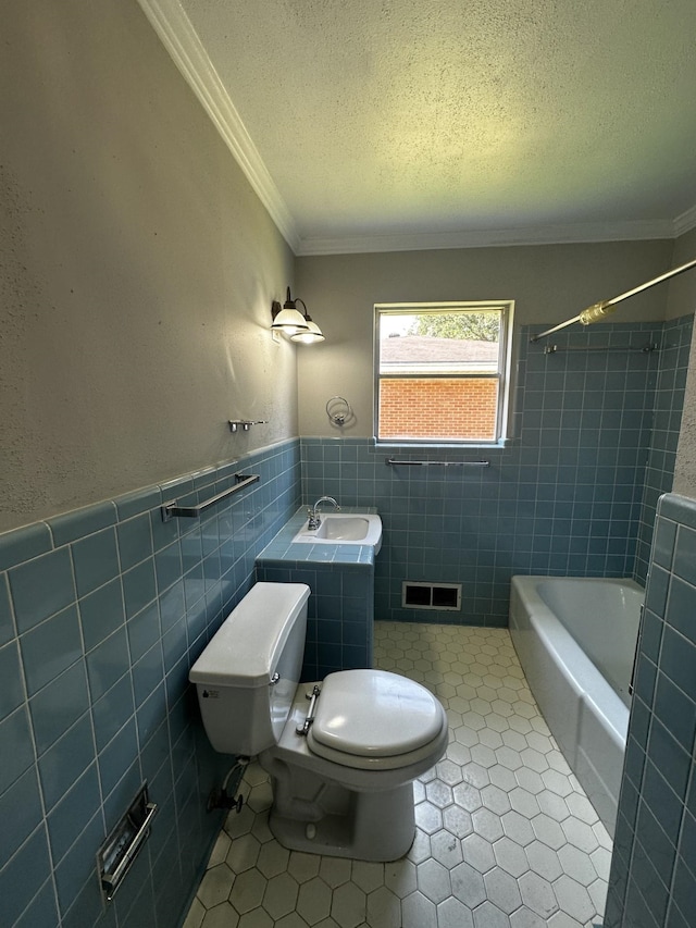 full bathroom with toilet, crown molding, tile walls, a textured ceiling, and sink