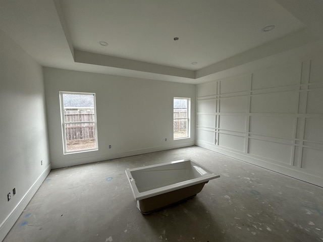 spare room with a tray ceiling and a healthy amount of sunlight