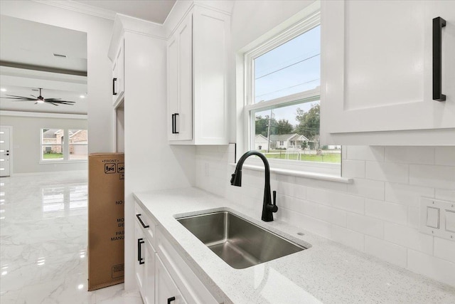 kitchen with backsplash, white cabinetry, light stone counters, and sink