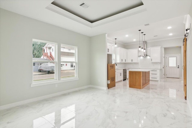 kitchen with white cabinetry, hanging light fixtures, wall chimney range hood, crown molding, and a kitchen island