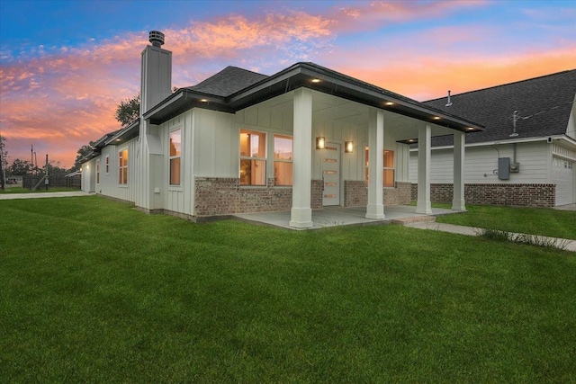 back house at dusk featuring a lawn