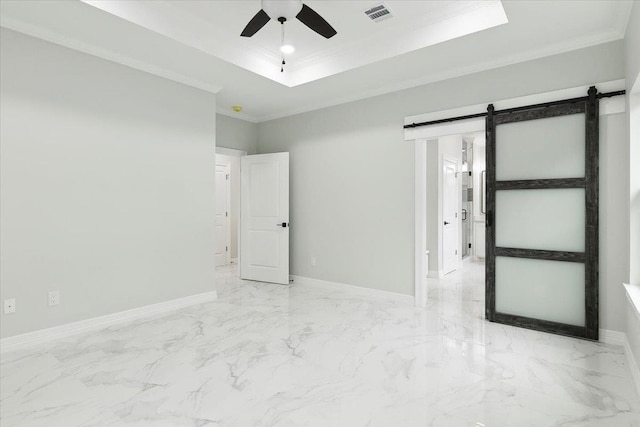 unfurnished room with ceiling fan, a barn door, a raised ceiling, and ornamental molding