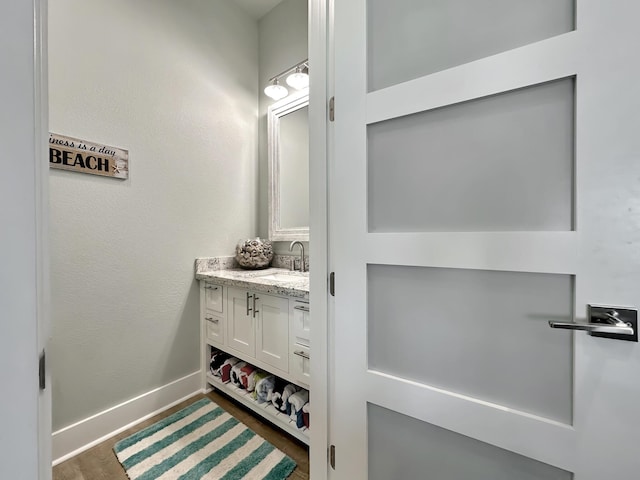 bathroom with vanity, baseboards, and wood finished floors