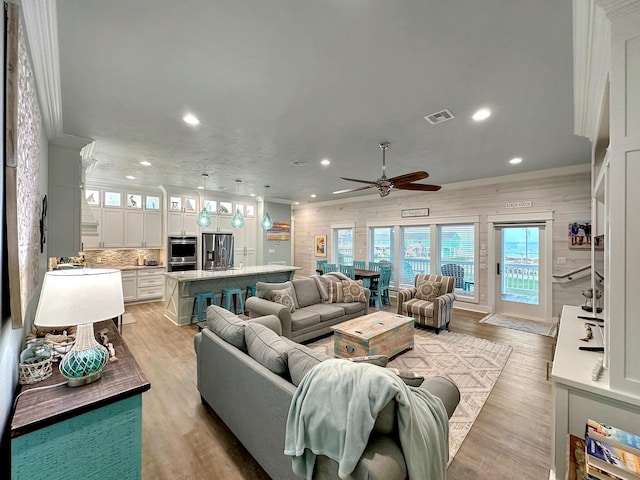 living area with recessed lighting, visible vents, ornamental molding, a ceiling fan, and light wood-type flooring