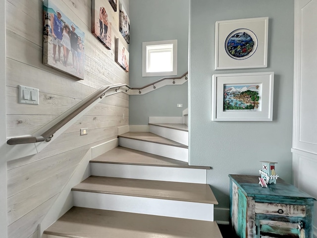 staircase featuring wood walls