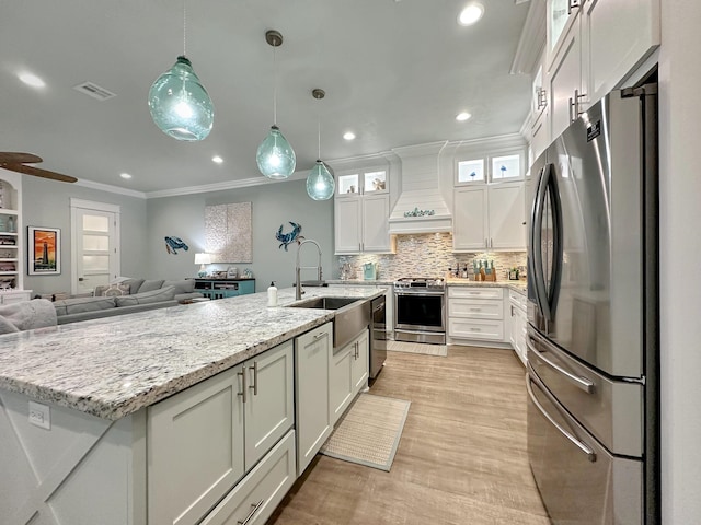 kitchen featuring visible vents, custom range hood, appliances with stainless steel finishes, open floor plan, and a sink