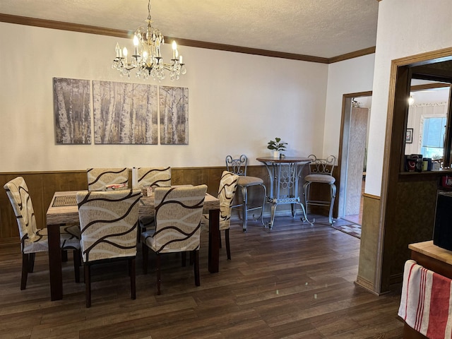 dining space with a textured ceiling, a wainscoted wall, wood walls, ornamental molding, and dark wood finished floors